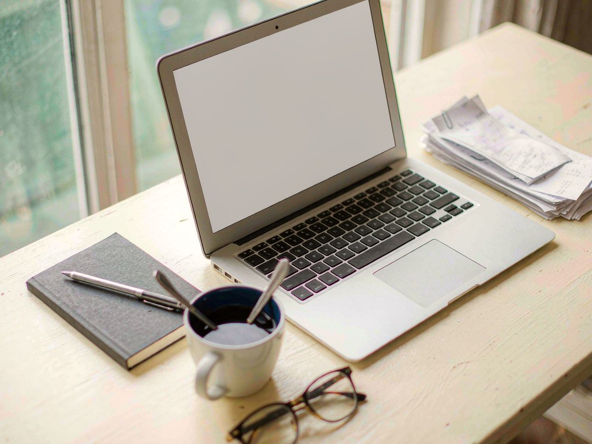A freelance professional's desk with a laptop, receipts and a notebook